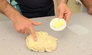 Man integrando mantequilla a la masa, un paso clave en la autolisis para un pan perfecto.