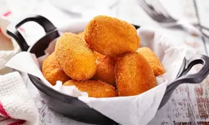 Croquetas doradas y crujientes en una sartén negra, listas para disfrutar.
