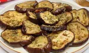 Rodajas de berenjena asada, tiernas y doradas, espolvoreadas con hierbas aromáticas. Un plato sencillo y delicioso para disfrutar del sabor de las berenjenas.