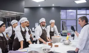 Chef instructor enseña a estudiantes a master food and beverage en una cocina profesional.