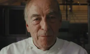 Retrato de un chef catalán con varias estrellas Michelin, con su uniforme blanco y mirada serena.
