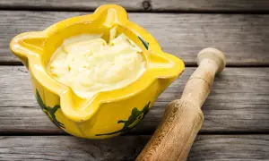 Alioli cremoso en mortero amarillo, listo para tu receta.