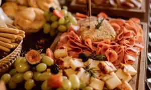 Un festín de quesos, embutidos, uvas, fresas y pan, un delicioso buffet para compartir.