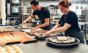 Dos cocineros preparan platos en una cocina profesional. ¿Cuánto gana un cocinero en Australia?
