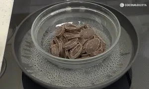 Chocolate troceado derritiéndose suavemente en un bol de cristal sobre un baño maría hirviendo.