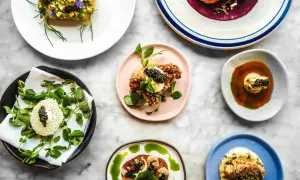 Deliciosos platos de un menú degustación, con caviar, flores comestibles y salsas vibrantes, presentados sobre una mesa de mármol.