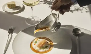 Servicio de sopa de marisco en un restaurante estrella Michelin. Un camarero vierte el caldo sobre un langostino y espuma.