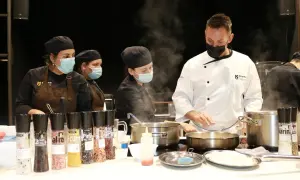 Un chef ejecutivo supervisa a su equipo en la cocina, rodeado de vapor y condimentos.