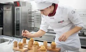Joven chef perfecciona pequeños bocados, demostrando su dominio en ciencias culinarias y gastronómicas.