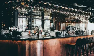 Barra de cobre pulido, botellas de licor, vasos y taburetes en este moderno bistro.
