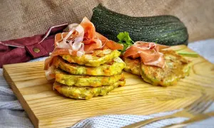 Deliciosas tortitas de calabacín apiladas y cubiertas con jamón serrano, listas para disfrutar.