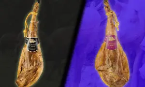 Dos jamones colgados, uno con etiqueta negra y otro con etiqueta morada, mostrando dos clases de jamón.