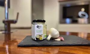 Tarro de alioli casero ecológico junto a una cabeza de ajo y dientes. ¡Este alioli se puede congelar para disfrutarlo más tiempo!
