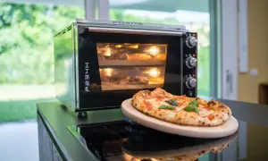 Horno eléctrico con dos pizzas dentro, una lista para disfrutar y otra en proceso. El tiempo de cocción de una pizza en horno eléctrico es clave para su textura.