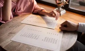 Pareja revisa el menú para decidir cómo hacer una carta de restaurante. Se ven platos como ensaladas y snacks.