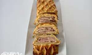 Delicioso hojaldre jamón york y queso al horno, cortado en porciones, con una capa crujiente y relleno jugoso.