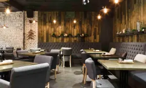 Interior de un restaurante de un tenedor con mesas de madera, sillas tapizadas y paredes de ladrillo y madera.