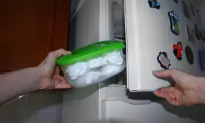Manos guardan un recipiente con merengues blancos en el congelador. Así se puede congelar el merengue para conservarlo.