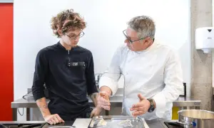 Un chef experimentado enseña a un joven aprendiz, mostrando diferentes tipos de chef en acción en una cocina profesional.