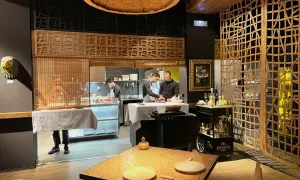 Chefs trabajan en la cocina de un restaurante. Se ve una mesa puesta y un carrito de bebidas. ¡Qué ganas de comer como Paco Méndez!