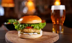 Deliciosa hamburguesa de pescado con lechuga, tomate y pepinillos, acompañada de una cerveza. ¿Cuánto tarda en descongelarse una hamburguesa?