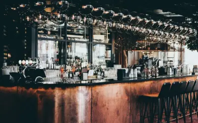 Barra de cobre pulido, botellas de licor, vasos y taburetes en este moderno bistro.