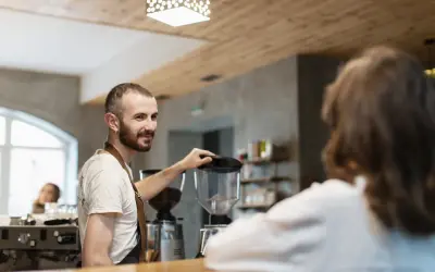 Barista sonríe mientras prepara café, un paso más para abrir su restaurante.