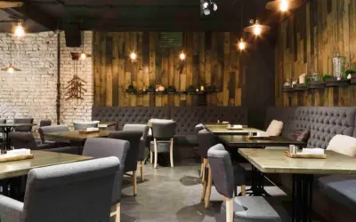 Interior de un restaurante de un tenedor con mesas de madera, sillas tapizadas y paredes de ladrillo y madera.
