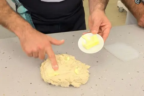 Man integrando mantequilla a la masa, un paso clave en la autolisis para un pan perfecto.