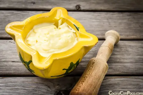Alioli cremoso en mortero amarillo, listo para tu receta.