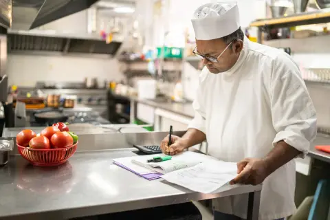 Chef calculando el coste de los ingredientes, un ejemplo de que es un escandallo en cocina.