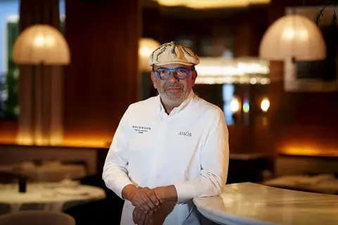 Un chef español con estrella Michelin, con gafas azules y gorra, posa en un elegante restaurante.