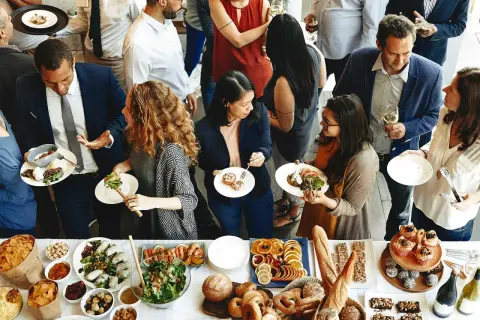 Gente disfrutando de la comida de personal en restaurantes, con una mesa llena de ensaladas, mariscos, frutas y pan.