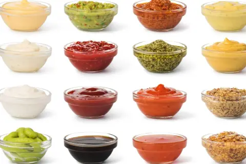Variedad de salsas y aderezos en cuencos de cristal. Ingredientes clave para emulsionantes naturales en la cocina, como mayonesa, guacamole y mostaza.