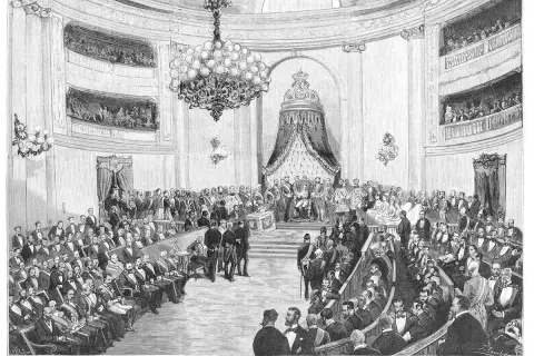 Sesión regia de apertura de Cortes en Madrid. La imagen ilustra un momento clave de la Restauración, con el rey en su trono y la cámara llena de asistentes.