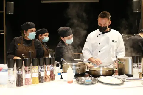 Un chef ejecutivo supervisa a su equipo en la cocina, rodeado de vapor y condimentos.