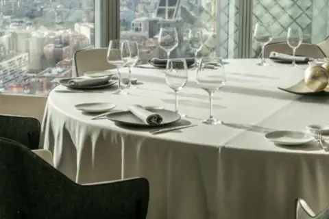 Mesa elegante en un restaurante con vistas a la ciudad, ideal para disfrutar de los mejores restaurantes de España.