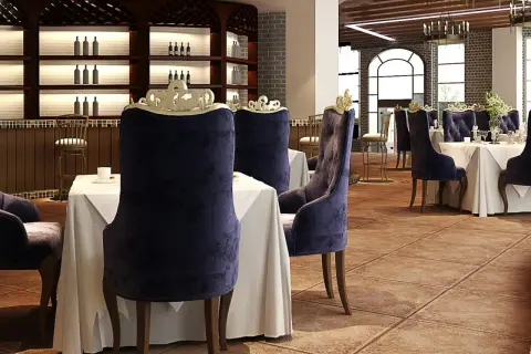 Elegantes sillas de terciopelo púrpura y mesas vestidas esperan a los comensales en este restaurante. El ambiente evoca nombres de restaurantes elegantes.
