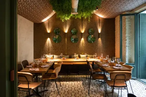 Elegante diseño de iluminación en restaurantes, con mesas puestas y vegetación colgante.