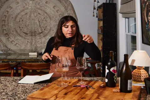 Mujer explicando cómo ser sommelier, con copas de vino y botellas en una mesa.