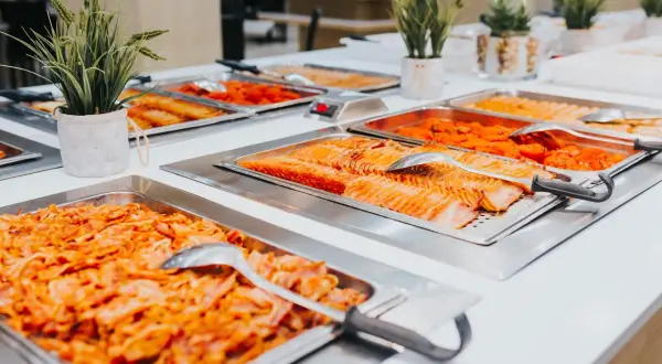 Bandejas de salmón y otros platos de quinta gama en un buffet.