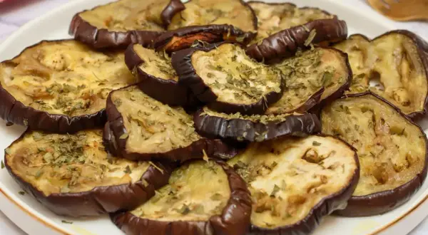Rodajas de berenjena asada, tiernas y doradas, espolvoreadas con hierbas aromáticas. Un plato sencillo y delicioso para disfrutar del sabor de las berenjenas.