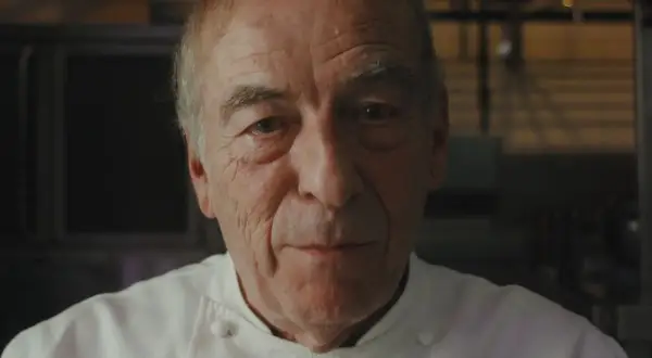 Retrato de un chef catalán con varias estrellas Michelin, con su uniforme blanco y mirada serena.