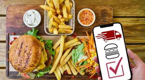 Hamburguesa, papas fritas y ensalada. El móvil muestra un camión de reparto y una hamburguesa, indicando que es rentable un negocio de comida para llevar.