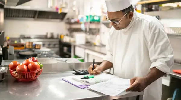 Chef calculando el coste de los ingredientes, un ejemplo de que es un escandallo en cocina.
