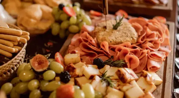 Un festín de quesos, embutidos, uvas, fresas y pan, un delicioso buffet para compartir.