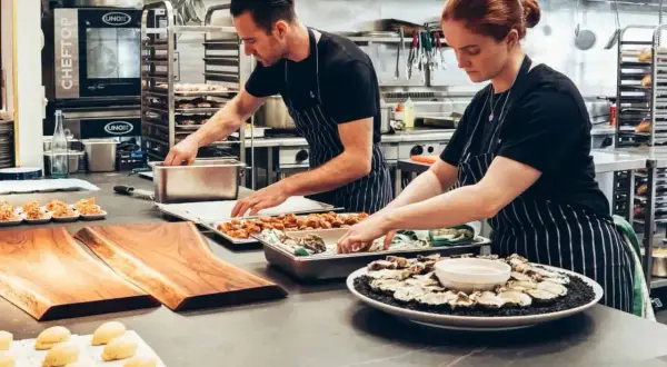 Dos cocineros preparan platos en una cocina profesional. ¿Cuánto gana un cocinero en Australia?