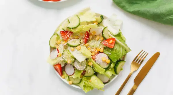 Ensalada fresca con fresas, pepino, rábano y maíz, perfecta para negocios de comida saludable. Cubierta con semillas de sésamo.