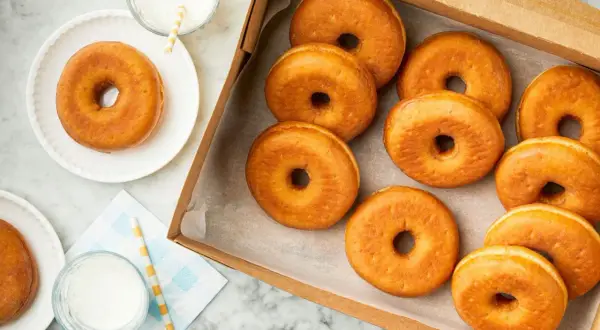 Una caja llena de deliciosos donuts dorados, perfectos para disfrutar o para saber que se pueden congelar los donuts y tenerlos listos para más tarde.