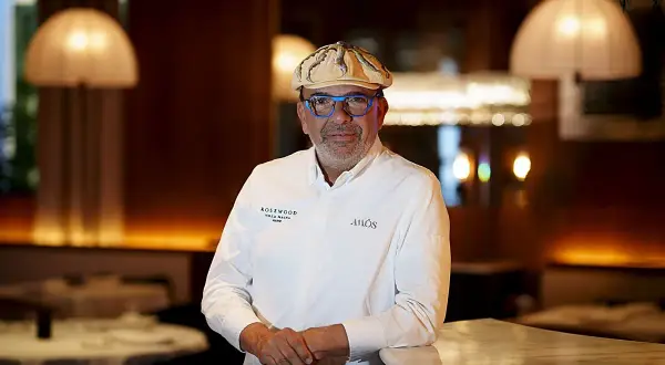 Un chef español con estrella Michelin, con gafas azules y gorra, posa en un elegante restaurante.